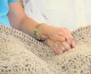 care team member and client holding hands
