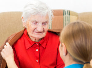 woman in red shirt having her coat put on